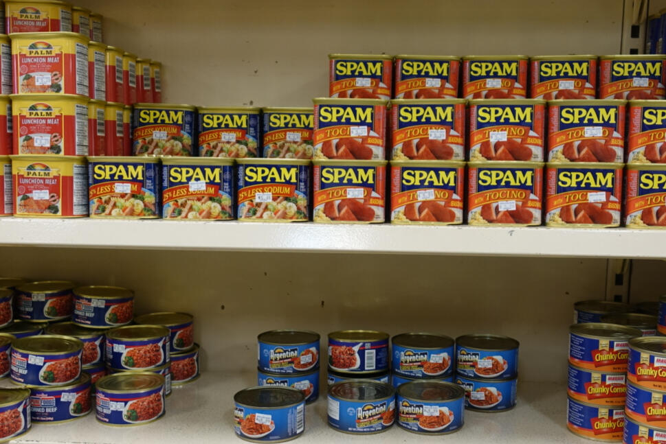 Asian grocery store shelves displaying various canned food like spam and corned beef.